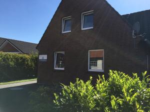 a red brick house with two windows and bushes at Ferienhaus Olenbrook in Cuxhaven