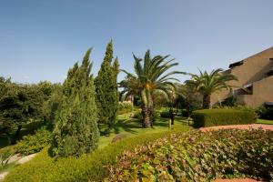 a garden with trees and bushes and a building at Appartamento Palau Alba in Palau