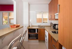 a kitchen with wooden cabinets and a sink and a microwave at Studio 2 Sea front in Rincón de la Victoria