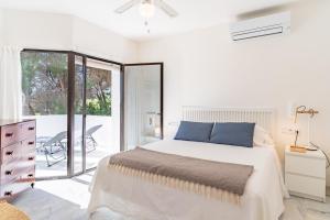 a white bedroom with a bed and a balcony at Ganso golf in Benalmádena