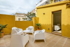 a patio with white chairs and a bed on a yellow building at Apartamento en el centro in Begur