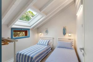 two beds in a room with a skylight at Saint Claude in Marina di Andora