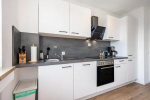 a white kitchen with white cabinets and a sink at Fewo Sonnenaufgang, Ausblick in Augsburg