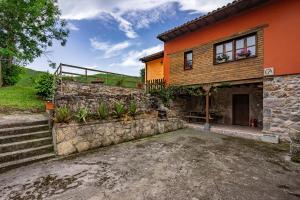 a house with a stone wall and stairs next to it at Casa Rural Ricao in Cangas de Onís