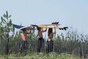 a group of people carrying surfboards on their backs at La Tomate Surfeuse 2 in Hourtin +2 photos