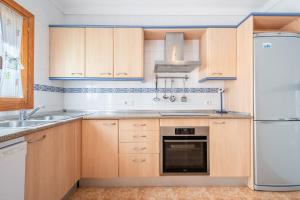 a kitchen with wooden cabinets and a refrigerator at Que Bo in Alcudia