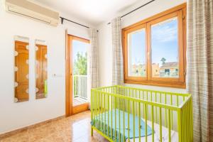 a green crib in a room with a window at Que Bo in Alcudia