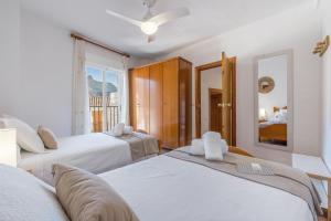 a bedroom with three white beds and a window at Casa Ramirez in Güéjar-Sierra
