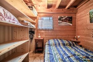 a log cabin bedroom with a bed and a window at Chalet 6p Classique - Le Marmotton in Verchaix
