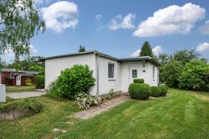 a white house in a yard with bushes at Bungalow 73 in Zadelsdorf