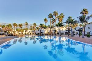 a swimming pool with palm trees and buildings at Horizon blu in Corralejo