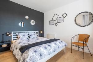 a bedroom with a bed and a chair and a mirror at Superbe Duplex en centre ville in Douarnenez
