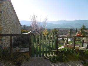 a wooden picket fence in a garden with mountains in the background at Maison - Le Rubato in Rosans