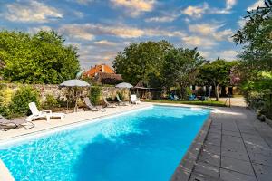 a swimming pool with chairs and umbrellas next to a house at Maison en pierre piscine clim in Varennes