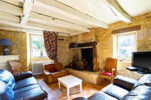 a living room with a couch and a tv at Maison en pierre piscine clim in Varennes