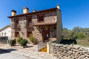 an old stone house with a stone wall at La Cárcava in La Serna del Monte