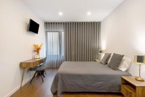 a bedroom with a bed and a desk and a computer at Jm Stay in Aveiro
