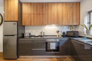 a kitchen with stainless steel appliances and wooden cabinets at Jm Stay in Aveiro