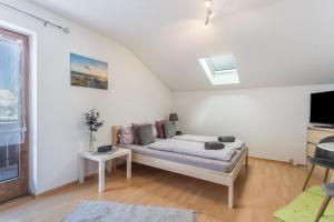 a white bedroom with a bed and a tv at Apartment Bergblick in Frasdorf