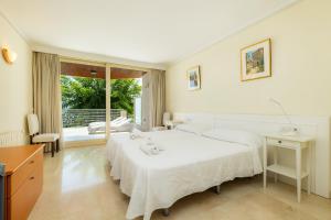 a bedroom with a large white bed and a balcony at Olympo in Port de Pollensa