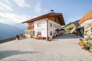 a large white building with a balcony on a patio at Tonigbauernhof Enzian in Schenna