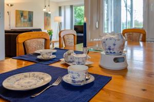 a table with plates and cups and a tea kettle at Ferienhaus 'am Gänsepfad' in Hage +20 photos