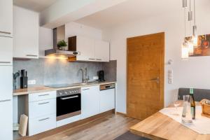 a kitchen with white cabinets and a wooden table at Apartment Bergglück Stummerberg in Stummerberg