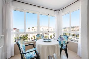 a dining room with a table and chairs and windows at Estudios 79 in Torrox