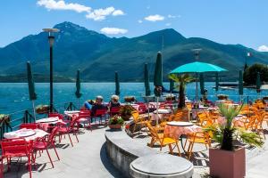 a restaurant with tables and chairs next to a body of water at Very Elegant Historic Apartment F2 in Gravedona
