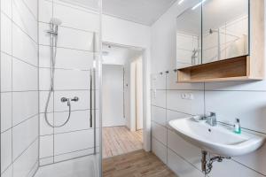 a white bathroom with a sink and a shower at Haus Kasberger in Ascheberg