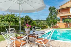 a table and chairs with an umbrella next to a swimming pool at Even Ezer with private pool in Pouládes