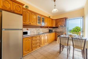 a kitchen with wooden cabinets and a table with chairs at Even Ezer with private pool in Pouládes