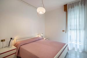 a bedroom with a pink bed and a window at Appartamento Passeggiata al Mare in Bibione