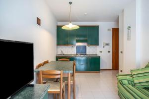 a kitchen with green cabinets and a table and chairs at Appartamento Passeggiata al Mare in Bibione