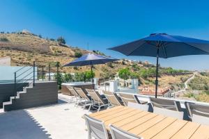 a patio with a wooden table and chairs with umbrellas at Luxury apartment in Cómpeta in Cómpeta +6 photos
