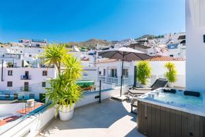 a balcony with a swimming pool and an umbrella at Luxury apartment in Cómpeta in Cómpeta