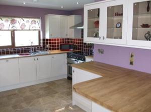 a kitchen with white cabinets and a stove top oven at Ty Talcen in Pennal