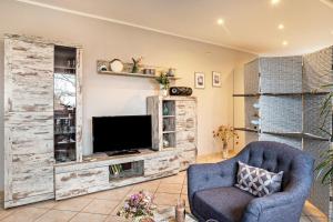 a living room with a tv and a blue chair at Ferienwohnung 'am Weidenring' in Pantelitz