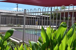 a white fence with a pool in front of a building at Southern Cross Motor Inn in Narrabri