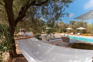a hammock next to a tree with a swimming pool at Domus mea salento Arazzo Rosso in Ugento +21 photos