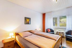 a bedroom with a bed and two chairs and a window at Ferienwohnung Kebben in Kirchhundem +30 photos