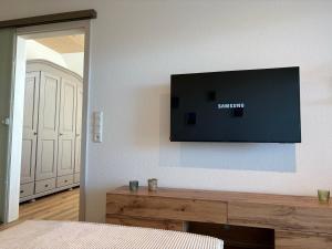 a flat screen tv on the wall of a bedroom at Ferienwohnungen Am Winkelhof in Deggenhausertal