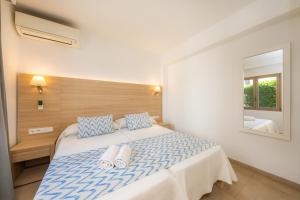a bedroom with a large bed with blue and white pillows at Apartamento Bon Aire N3 in Cala Ferrera +13 photos