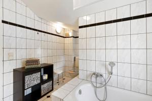 a white tiled bathroom with a tub and a toilet at Ferienwohnung in Potsdam in Potsdam +15 photos