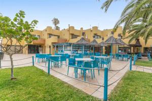 a restaurant with blue tables and chairs in front of a building at Casa Del Caballero Corralejo in Corralejo