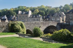 a stone bridge with two benches in a park at Le Douar Armor - cour intérieure in Dinan