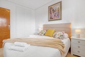 a white bedroom with a large bed with towels on it at Parque Mar V in La Mata +12 photos