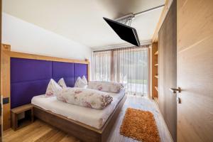 a bedroom with a large bed with a purple headboard at Residence Latemarblick in Nova Levante