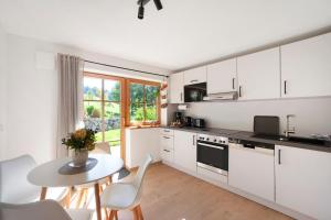 a kitchen with white cabinets and a table with chairs at Allpano Pension und Ferienwohnungen in Dietmannsried