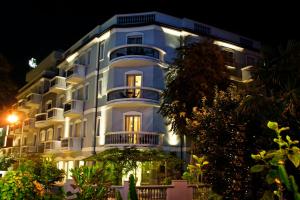 a large white building at night with lights at Sovrana Hotel & SPA in Rimini